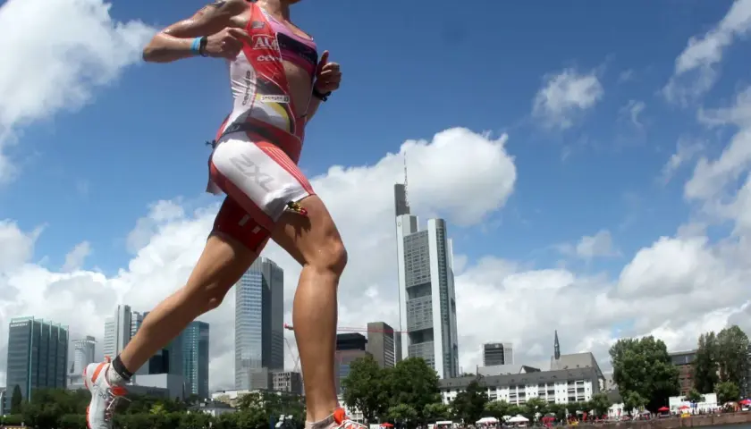 Läuferin im Triathlon-Anzug absolviert intensives Marathon-Training vor Frankfurter Skyline.