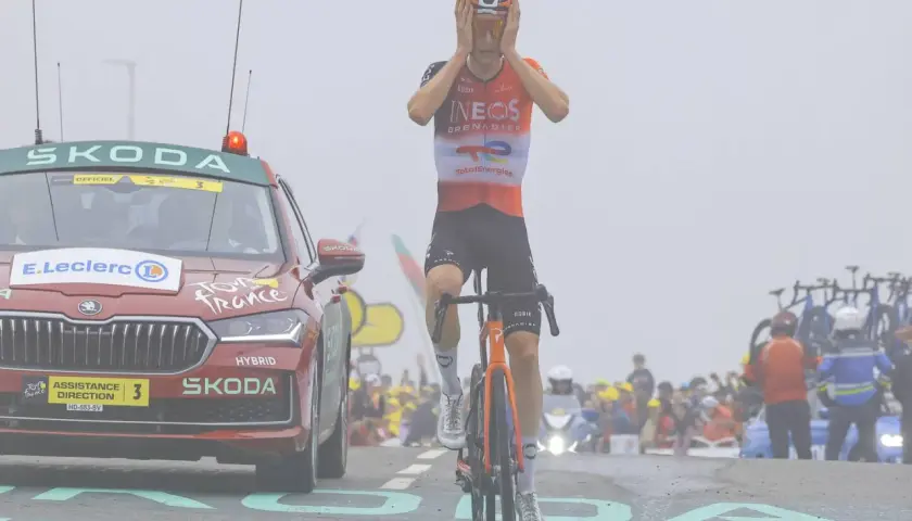Ein Tour de France Fahrer mit Händen am Kopf, neben einem Skoda Begleitfahrzeug.