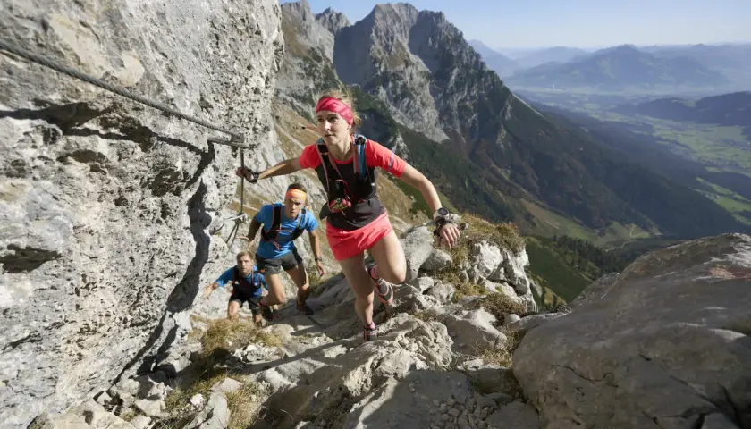 Trailrunner meistern den anspruchsvollen Kaiserkrone Trail, gesichert durch Stahlseile, mit atemberaubendem Blick ins Tal.