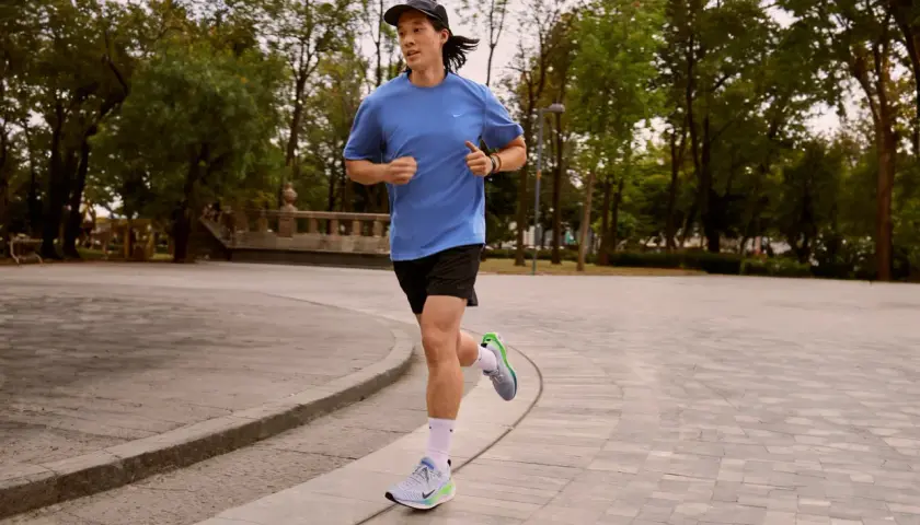 Läufer mit pronation fuss im Park, der auf einem gepflasterten Weg joggt.