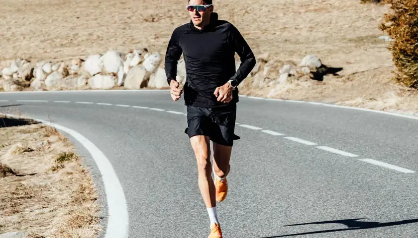 Jan Frodeno läuft auf einer Straße, seine leuchtend orangen Jan Frodeno Schuhe sind gut sichtbar.