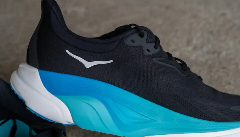Schwarzer Hoka Arahi 8 Laufschuh mit weißem Logo und auffälliger blau-weißer Sohle.