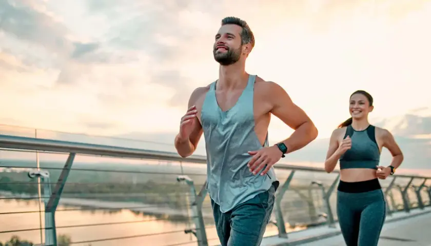 Ein Paar joggt auf einer Brücke bei Sonnenaufgang. Sie folgen einem ausgewogenen joggen und krafttraining wochenplan für ihre Fitness.