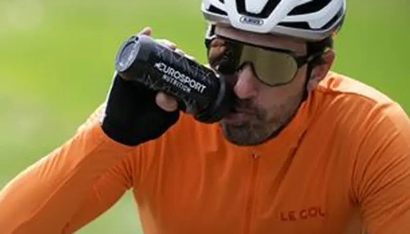 Radfahrer trinkt aus Flasche bei italienischem Radsportereignis.