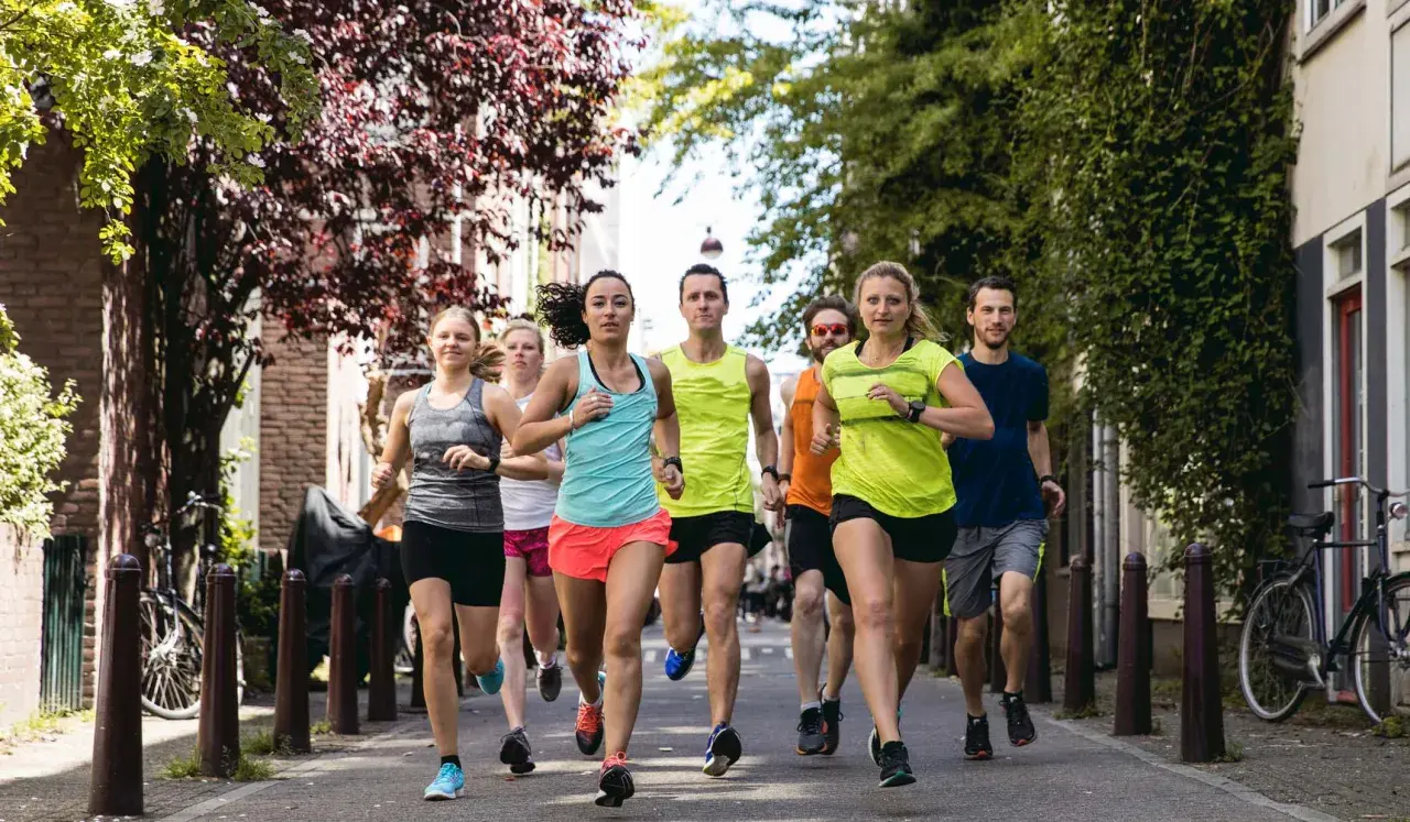 Eine Gruppe von Läufern trainiert für ihren nächsten laufzeit marathon auf einer malerischen Straße mit Bäumen und Häusern.