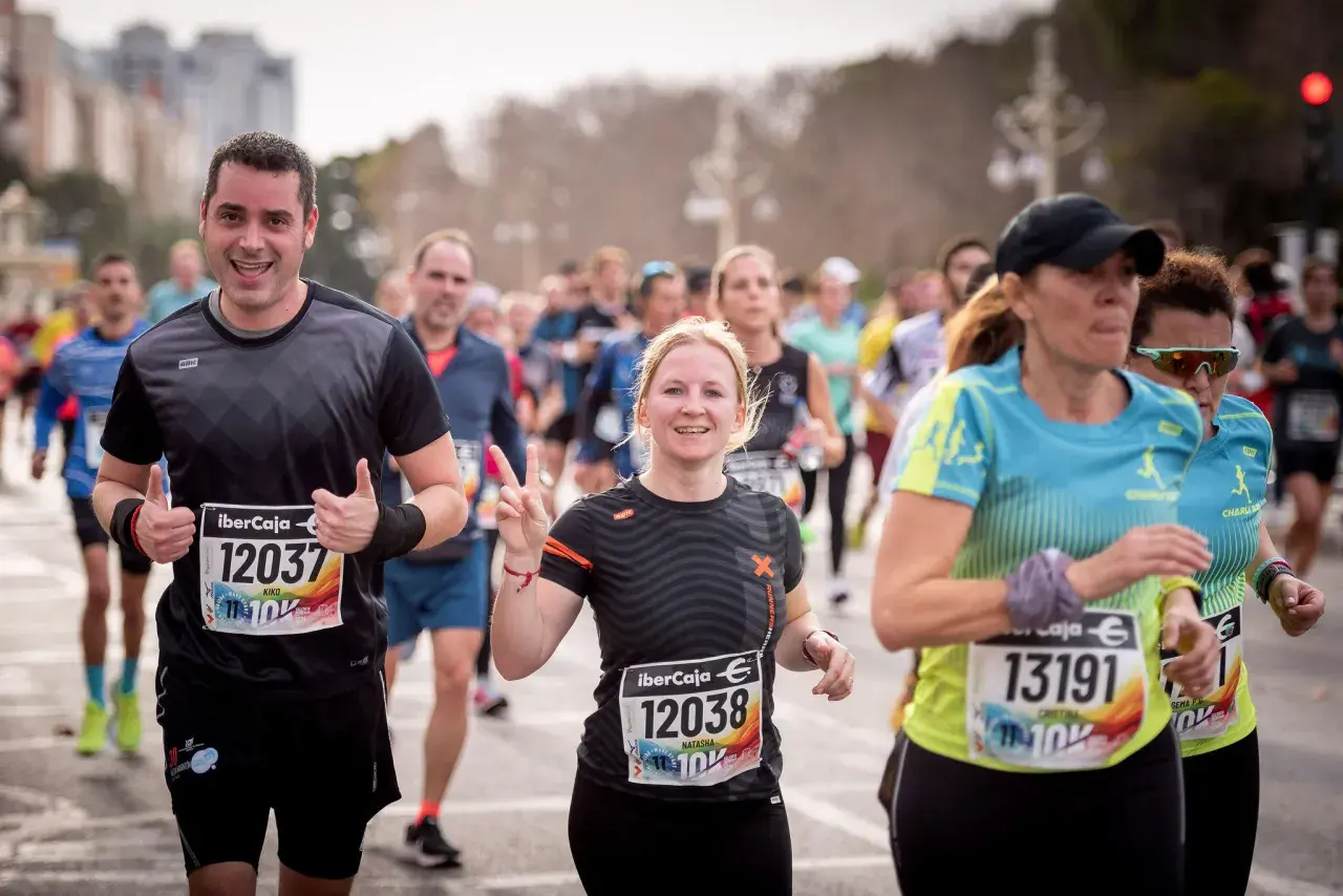 Läufer beim 10 km lauf. Ein Mann jubelt, eine Frau zeigt die Friedensgeste.