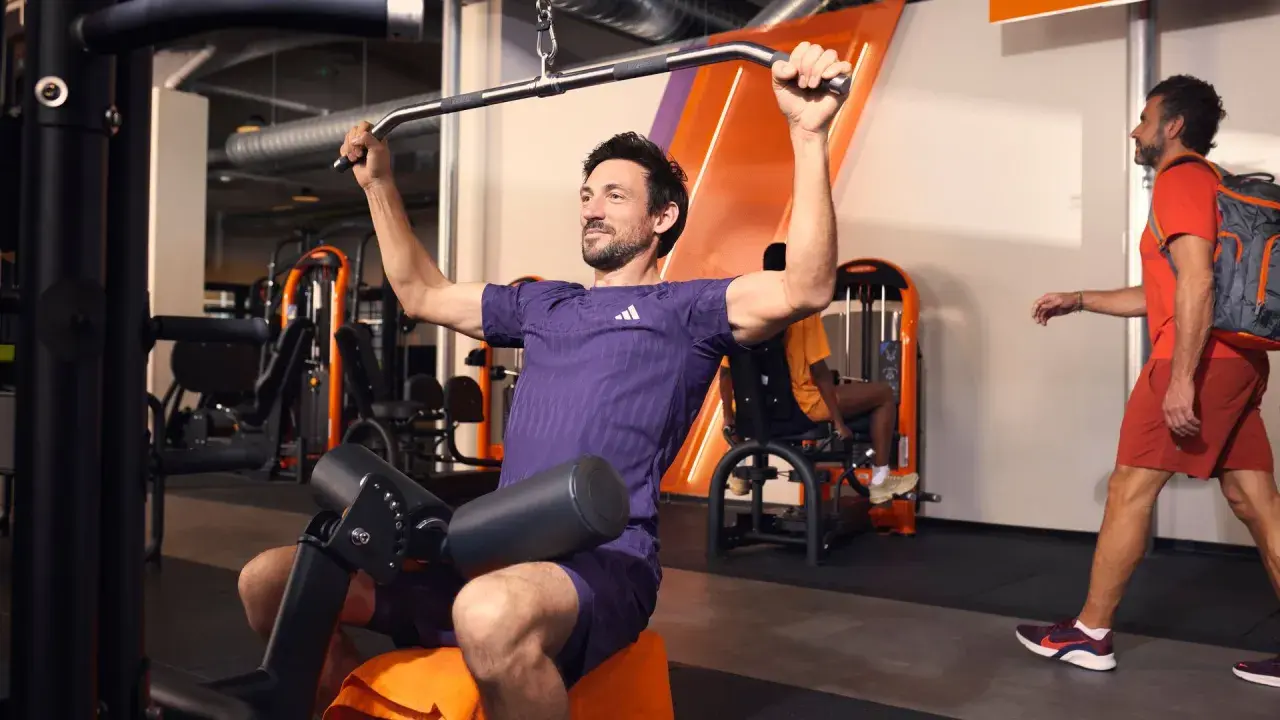 Mann trainiert im Fitnessstudio an einer Latzugmaschine. Effektives Cardio zum Abnehmen und Muskelaufbau.