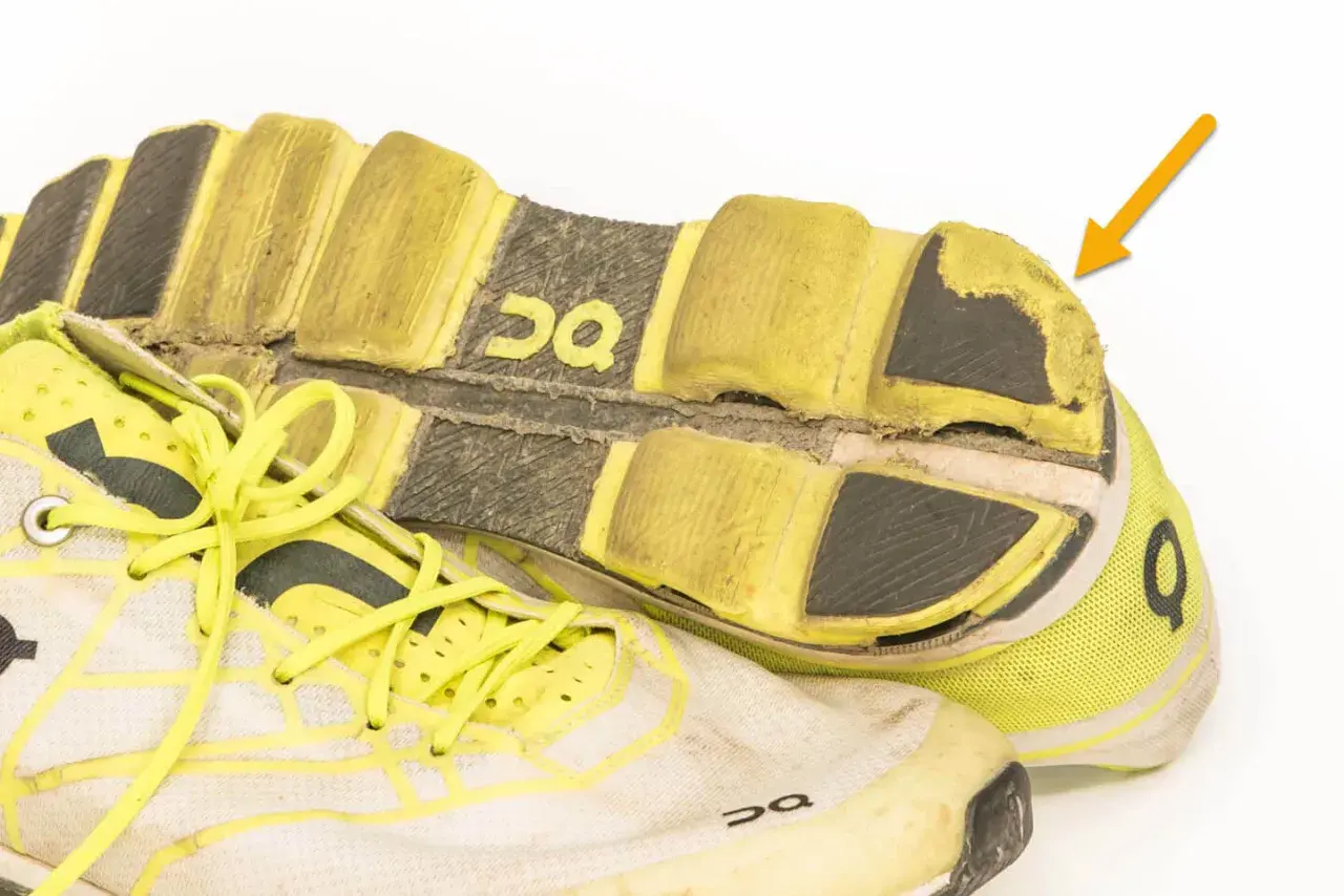 Abgenutzte Laufschuhe mit gelben Schnürsenkeln und deutlichen Abnutzungsspuren an der Sohle. Wie viele km haben diese Schuhe wohl schon hinter sich?