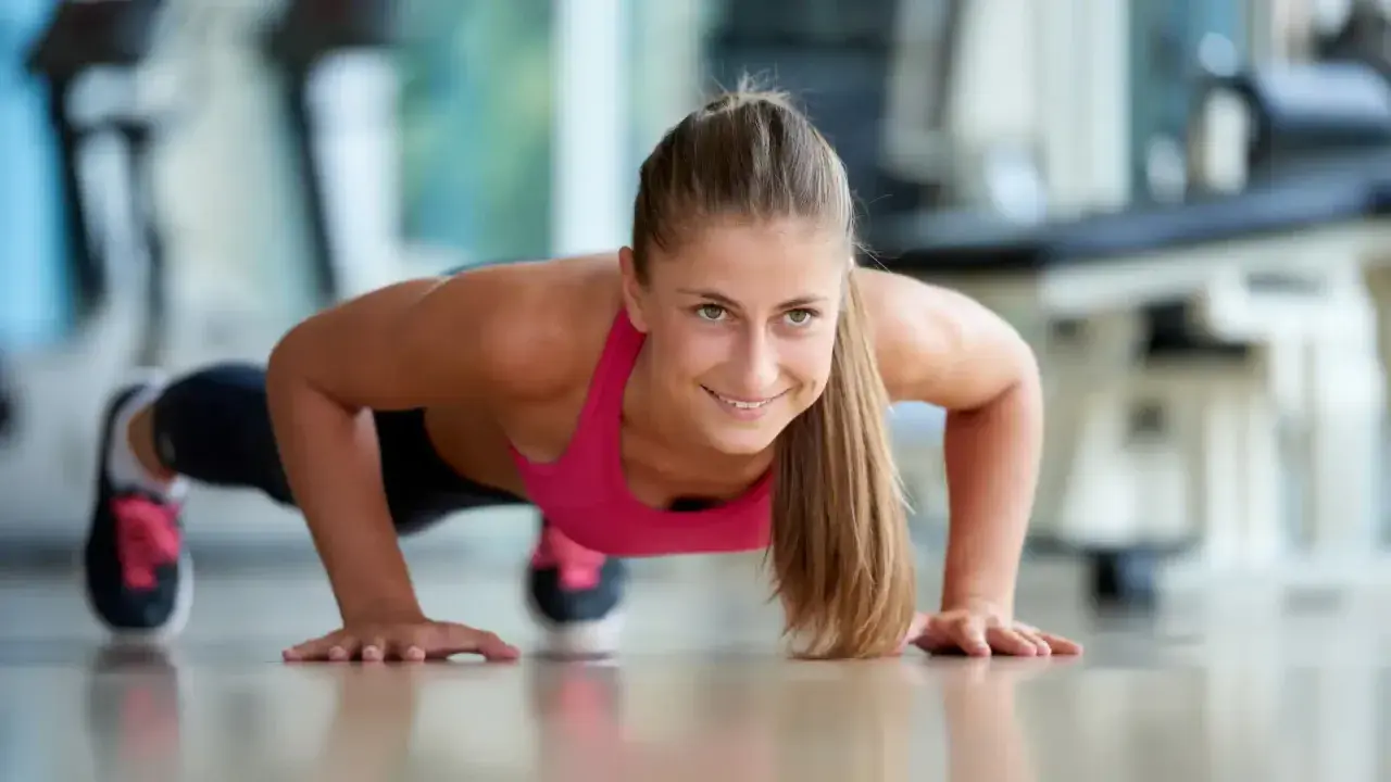 Frau macht Liegestütze, fokussiert und stark. Mentales Training im Sport hilft, solche Ziele zu erreichen.