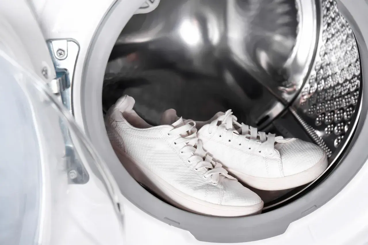 Weiße laufschuhe warten in der waschmaschine auf ihre Reinigung.