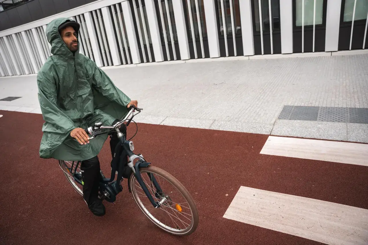 Mann mit Kapuze fährt mit einem Rennrad bei Regen.
