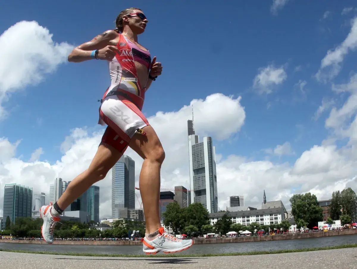 Läuferin im Triathlon-Anzug absolviert intensives Marathon-Training vor Frankfurter Skyline.