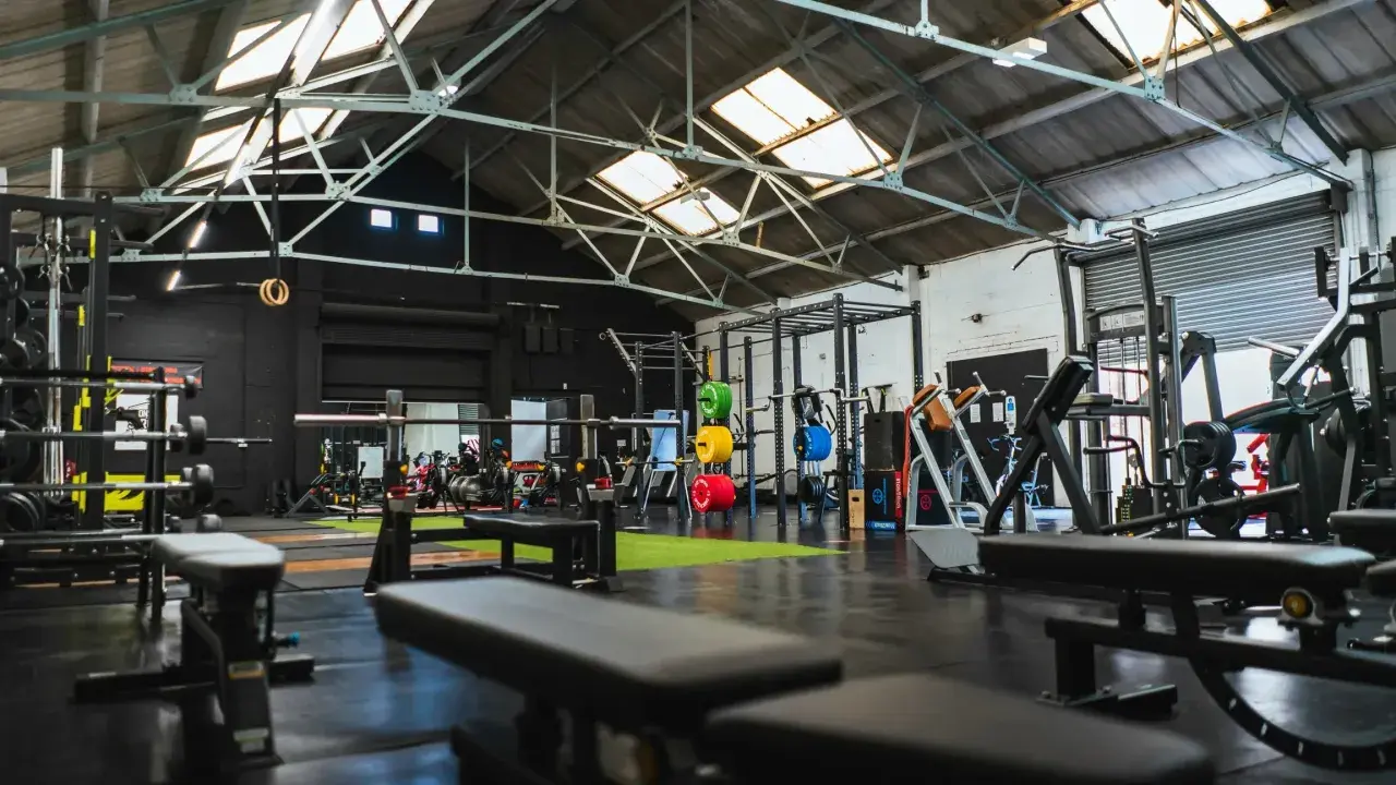 Gerät für Cardio und Muskelaufbau in einem modernen Fitnessstudio mit Hanteln, Gewichten und Trainingsbänken.