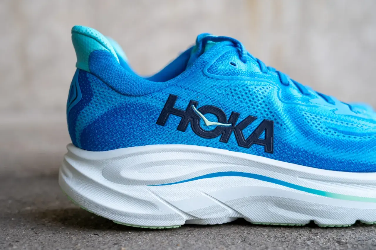 Blauer Hoka Laufschuh mit markantem Logo und dicker, weißer Sohle.