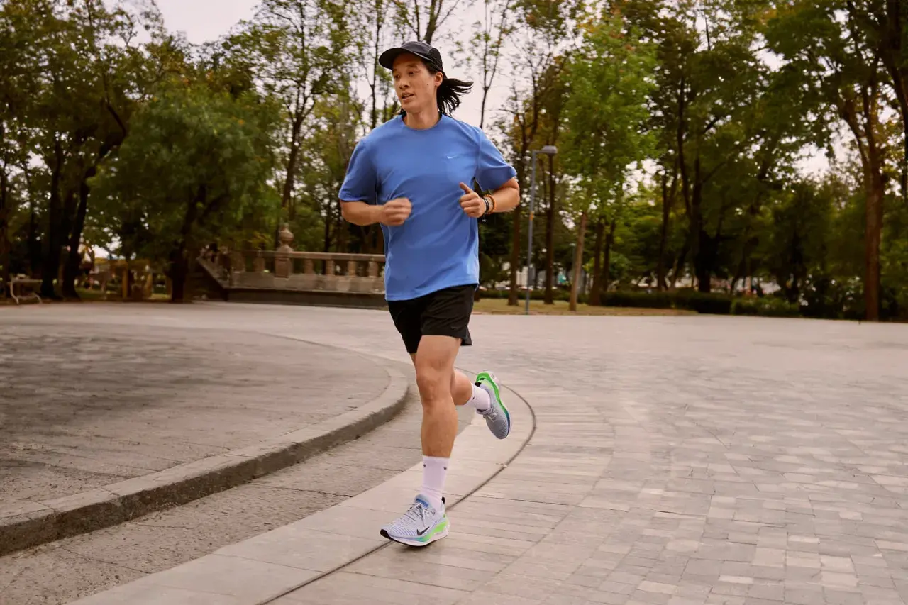 Läufer mit pronation fuss im Park, der auf einem gepflasterten Weg joggt.