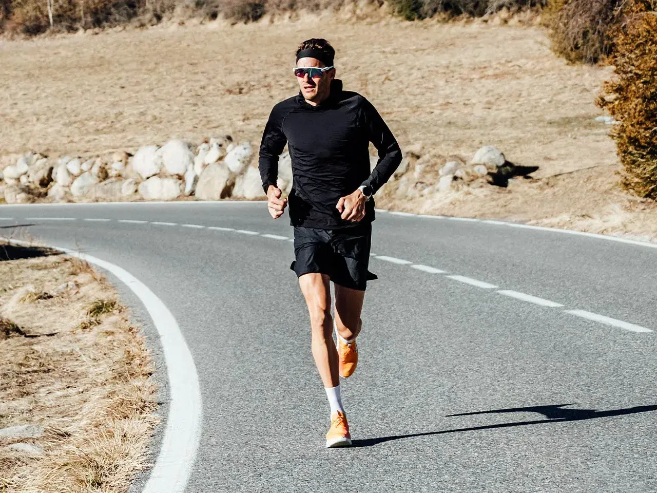 Jan Frodeno läuft auf einer Straße, seine leuchtend orangen Jan Frodeno Schuhe sind gut sichtbar.