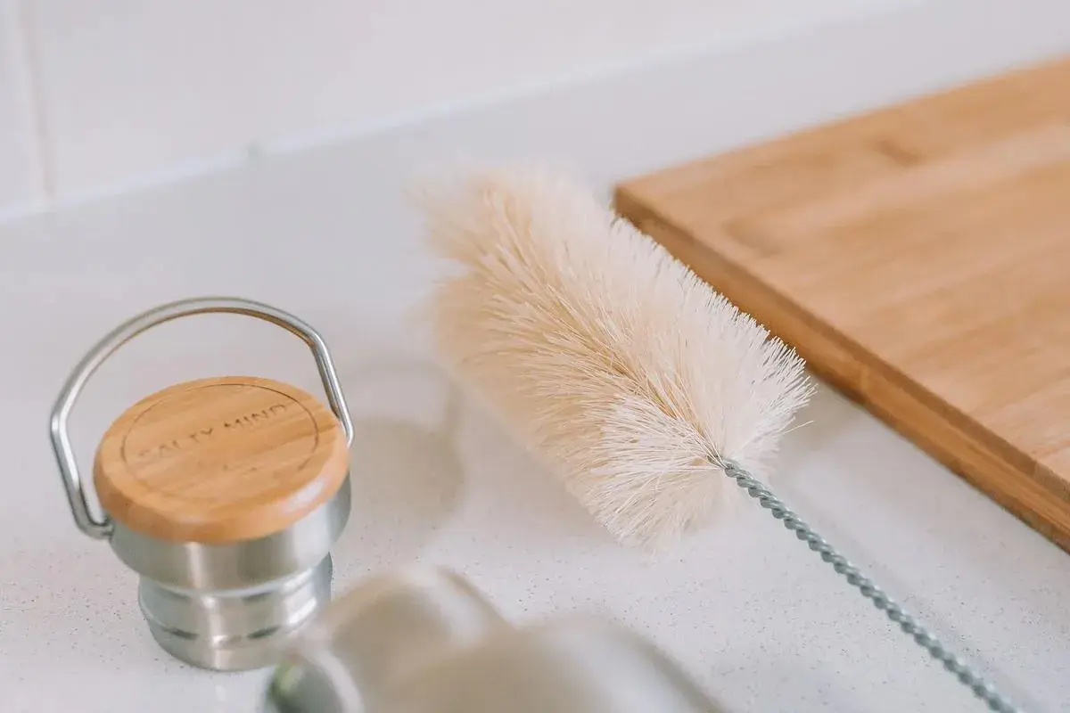 Eine Bürste liegt bereit, um die Trinkflasche zu reinigen. Daneben ein Holzbrett.