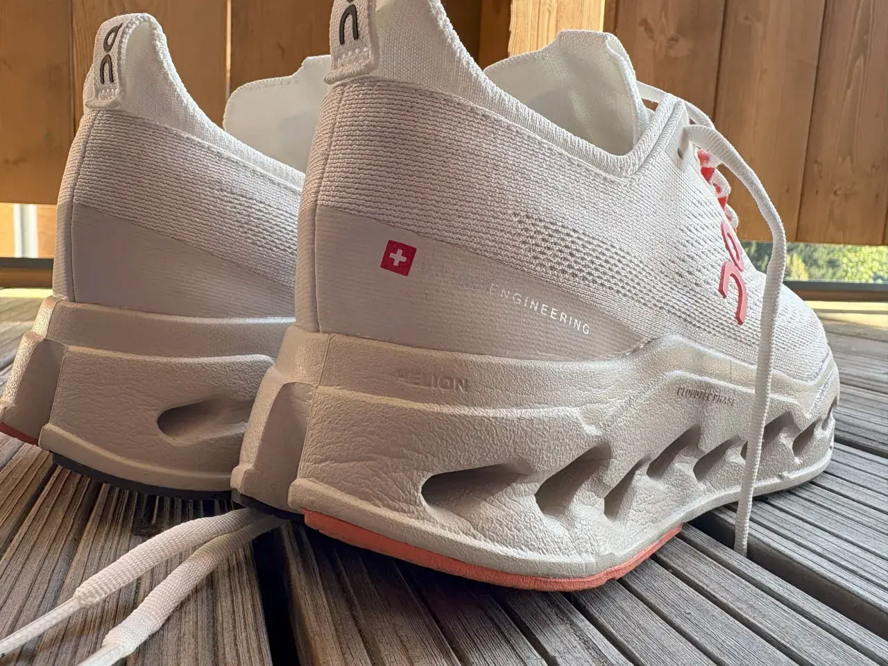 Weiße Laufschuhe, On Cloudsurfer Max, mit markanter Sohle und Schweizer Kreuz-Detail.