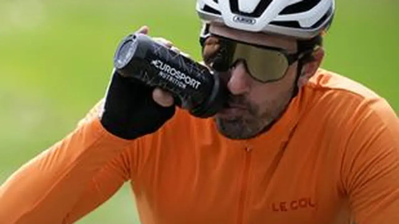 Radfahrer trinkt aus Flasche bei italienischem Radsportereignis.
