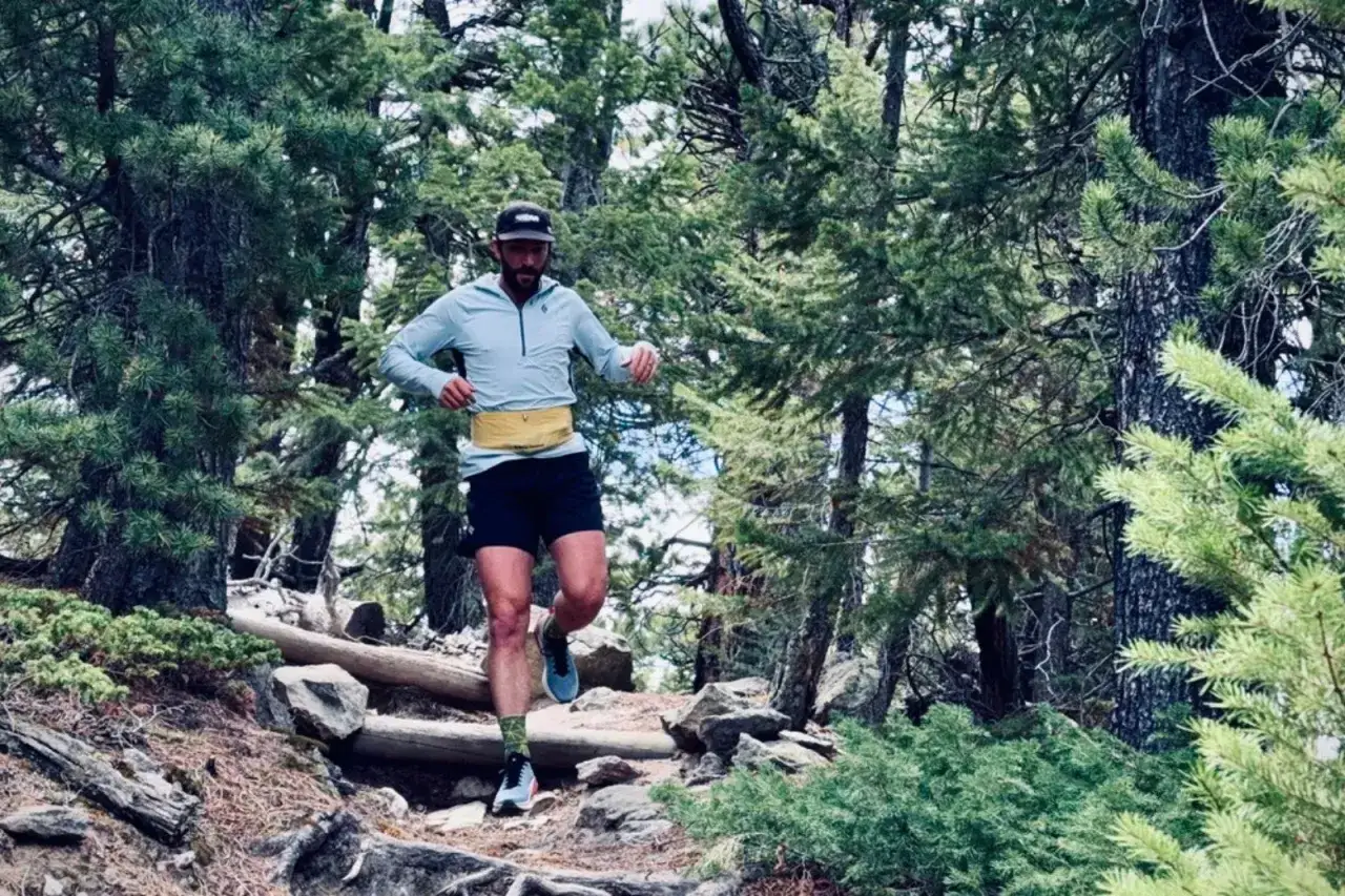 Mann beim trail running auf einem steinigen Waldweg, umgeben von B&auml;umen.