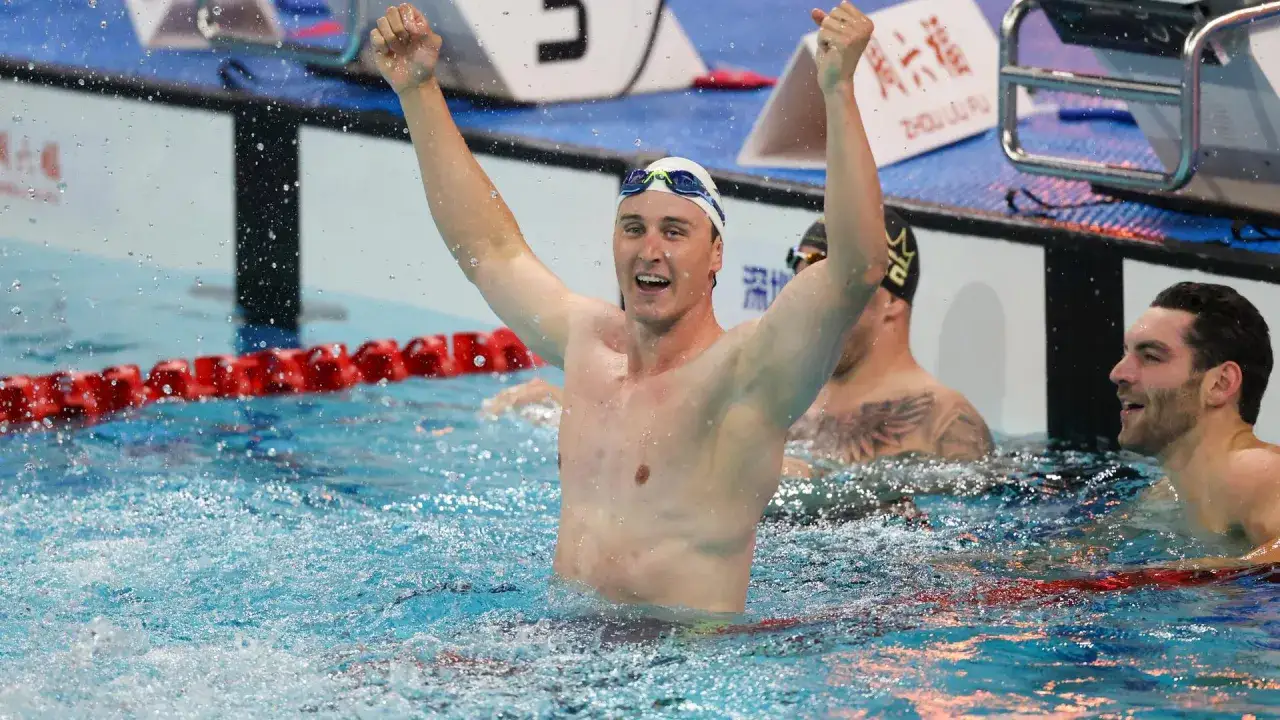 Schwimmer jubelt nach dem 1km Schwimmen. Die durchschnittliche Zeit ist beeindruckend.