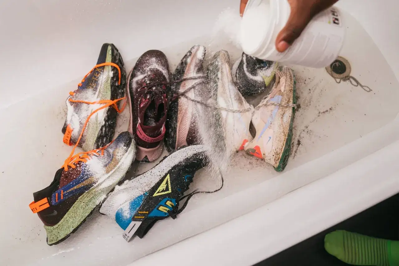 Mehrere Laufschuhe werden in einer Wanne mit Reinigungspulver bestreut, als ob sie in einer Waschmaschine gereinigt w&uuml;rden.
