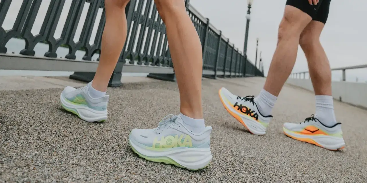 L&auml;ufer mit Hoka Schuhen auf einem Weg. Die Schuhe sind in Wei&szlig; mit leuchtenden Akzenten.