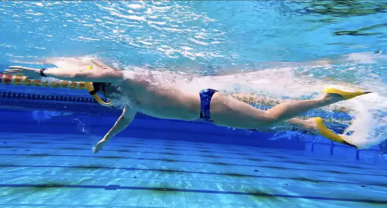 Schwimmer mit Schnorchel und Flossen gleitet durch das Wasser. Die gelben Flossen treiben ihn voran, w&auml;hrend er mit den Armen paddelt.