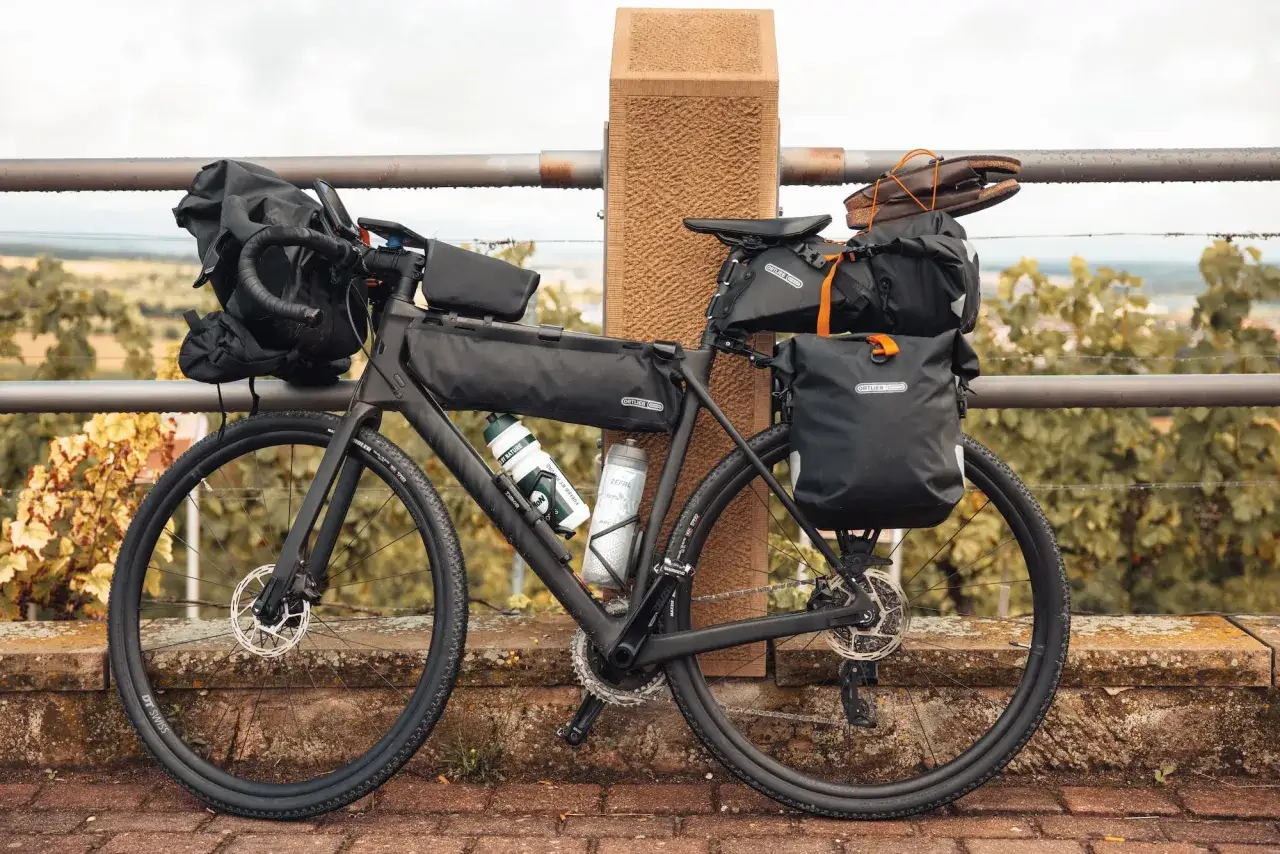 Bereit f&uuml;r ein Abenteuer: Ein voll ausgestattetes Gravelbike f&uuml;r Bike Packing mit Ortlieb-Taschen, Trinkflaschen und sogar Schuhen auf dem Gep&auml;cktr&auml;ger.