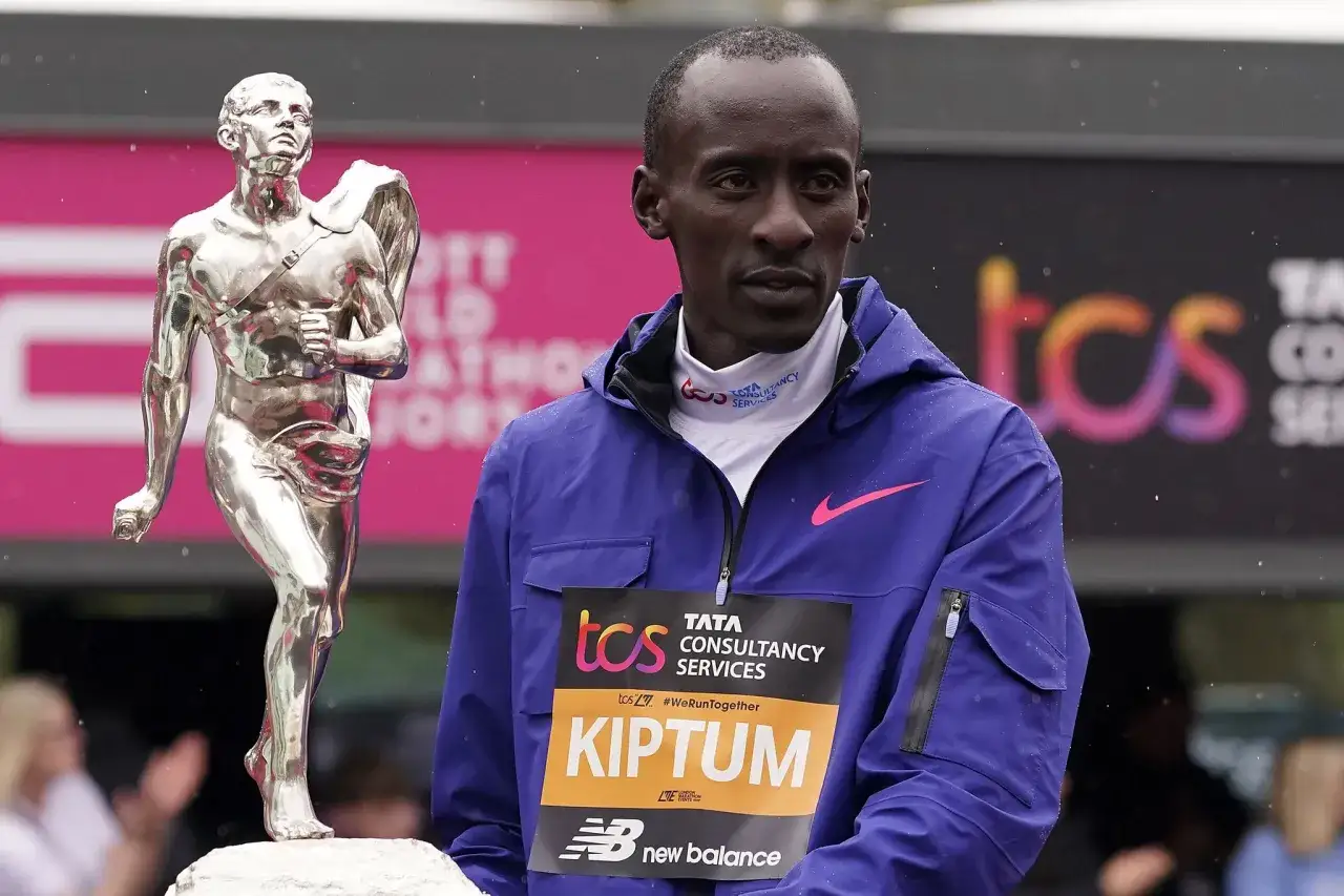 Kelvin Kiptum steht neben einer silbernen Troph&auml;e, tr&auml;gt eine blaue Jacke mit seinem Namen und dem Logo von TCS.