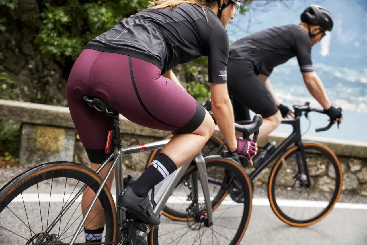 Zwei Radfahrerinnen auf einer Bergstra&szlig;e. Die vordere tr&auml;gt eine bordeauxrote Radhose, die &uuml;ber einer d&uuml;nnen Unterhose getragen wird.