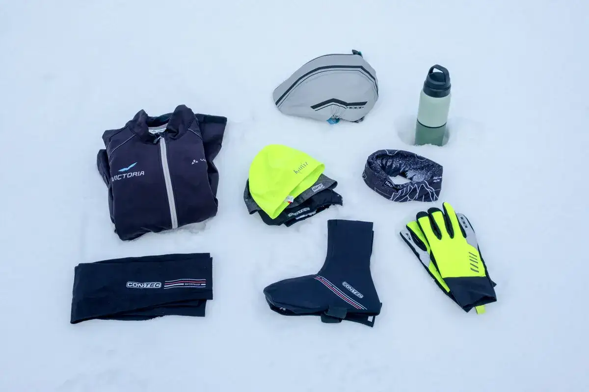 Winterkleidung f&uuml;r das Rennrad: Jacke, M&uuml;tze, Handschuhe, &Uuml;berschuhe, Trinkflasche und mehr, bereit f&uuml;r eisige Touren.