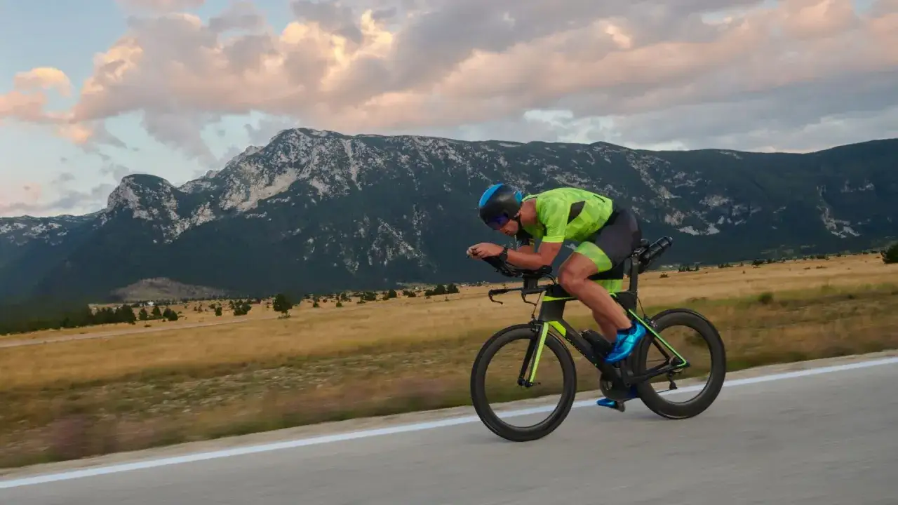 Ein Radfahrer im aerodynamischen Rennrad-Outfit absolviert sein Rennrad Training vor einer beeindruckenden Bergkulisse.
