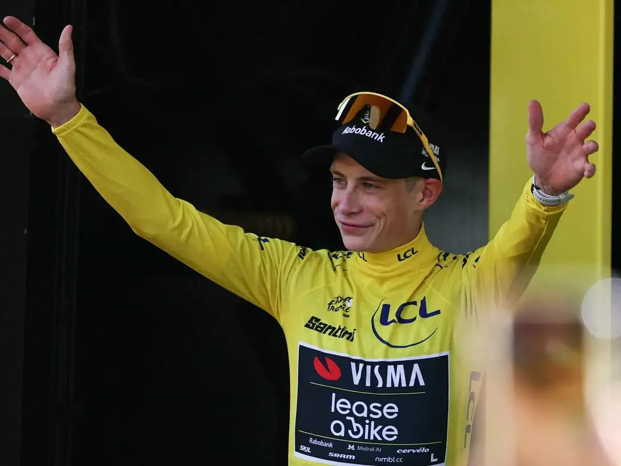 Radfahrer im gelben Trikot, Sieger der Tour de France Gesamt, jubelt mit erhobenen Armen.