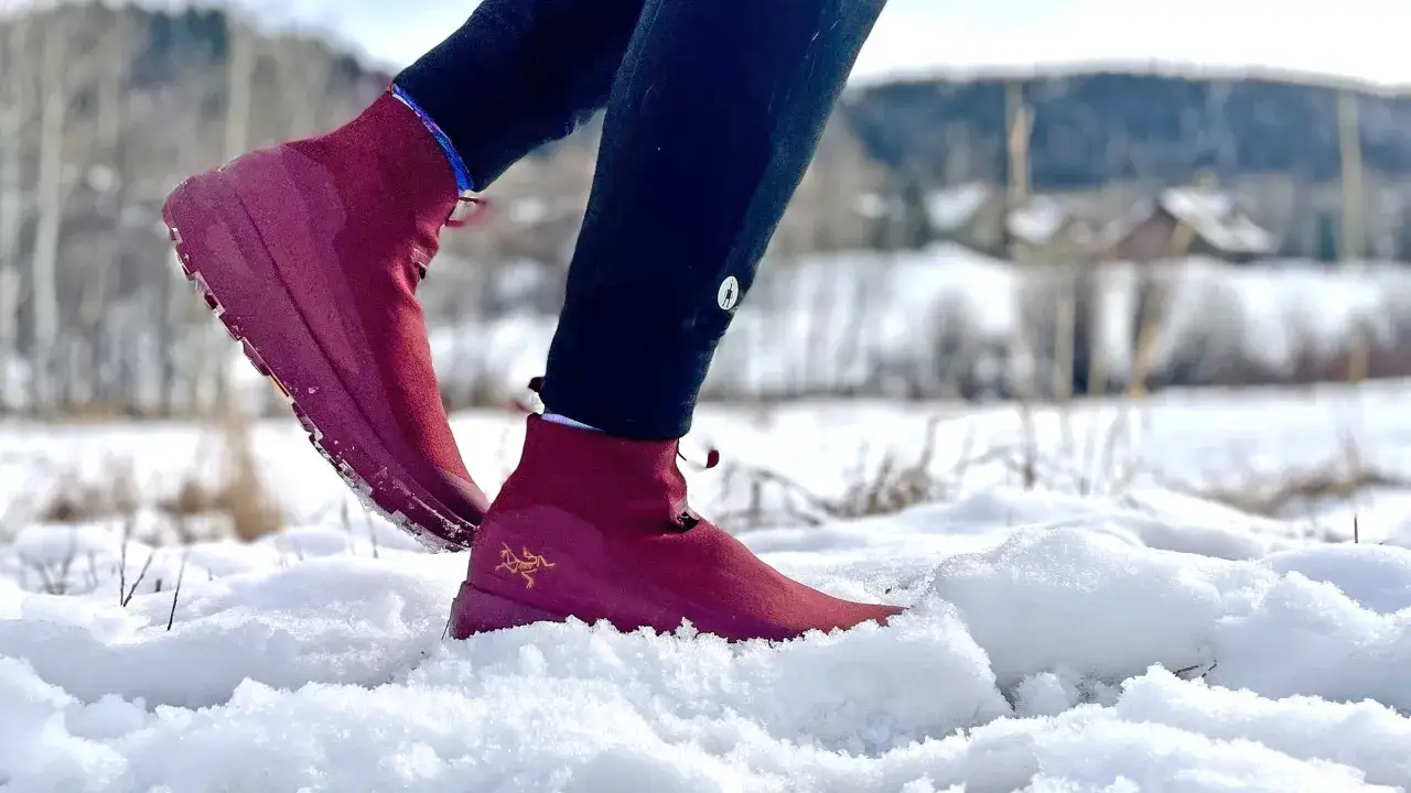 Rote Schnee Laufschuhe mit goldenem Logo im tiefen Schnee.